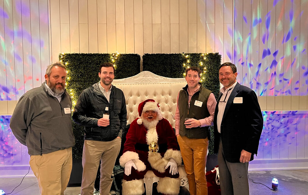 Group of men posing with Santa Claus at a festive event.