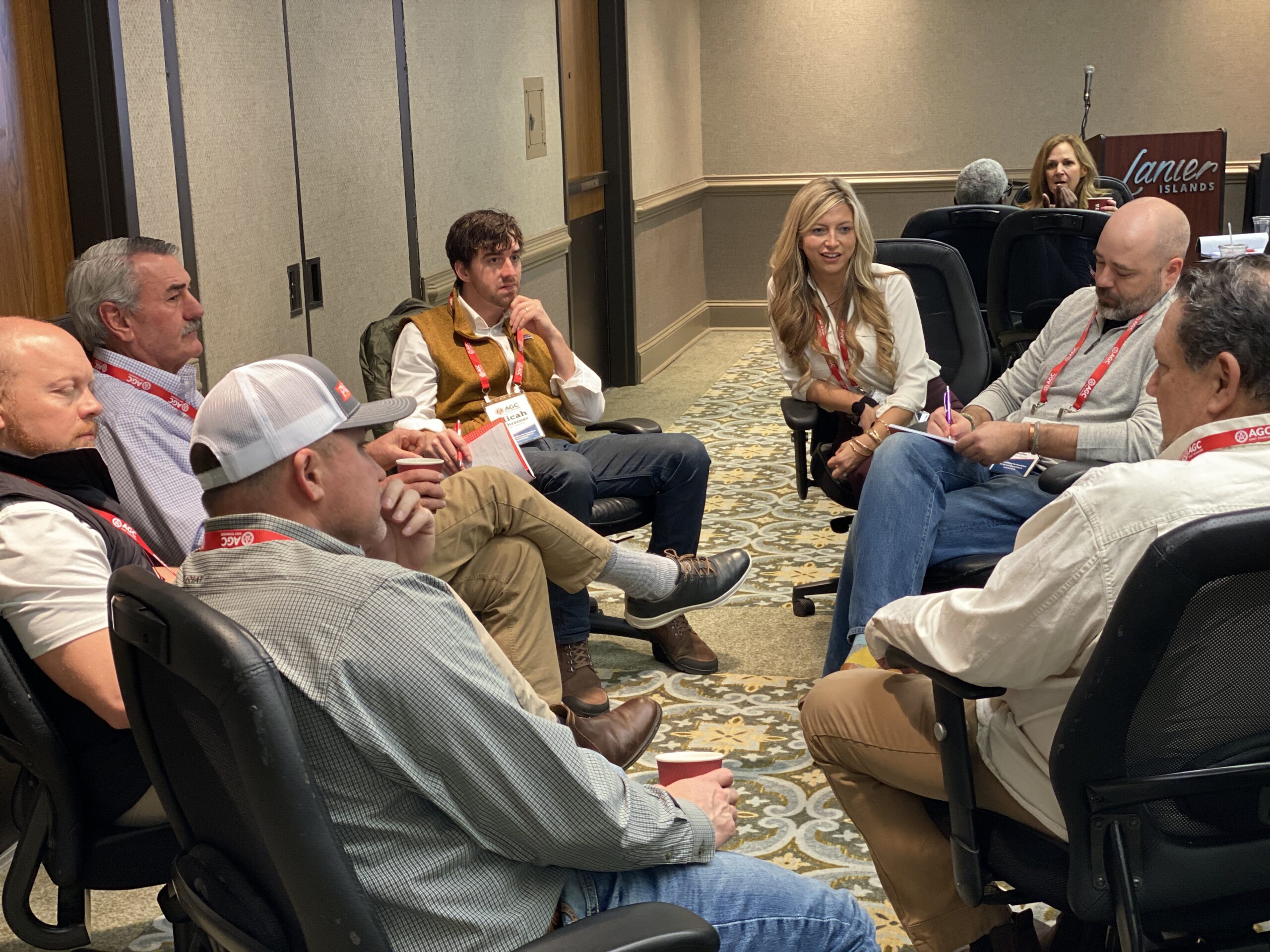 A group of people sitting in a circle, engaged in conversation in a casual setting.