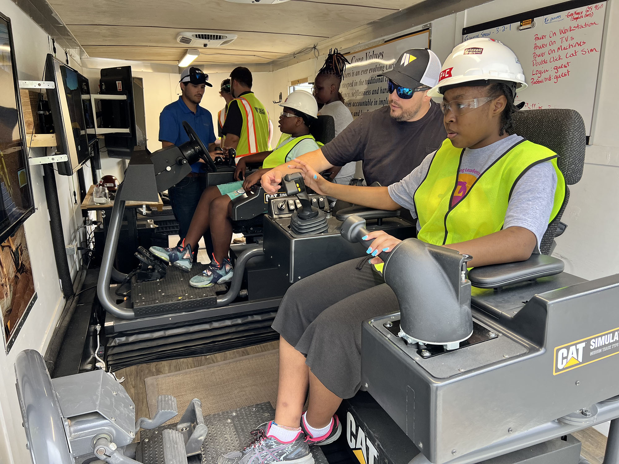 People wearing safety gear operating machinery indoors.